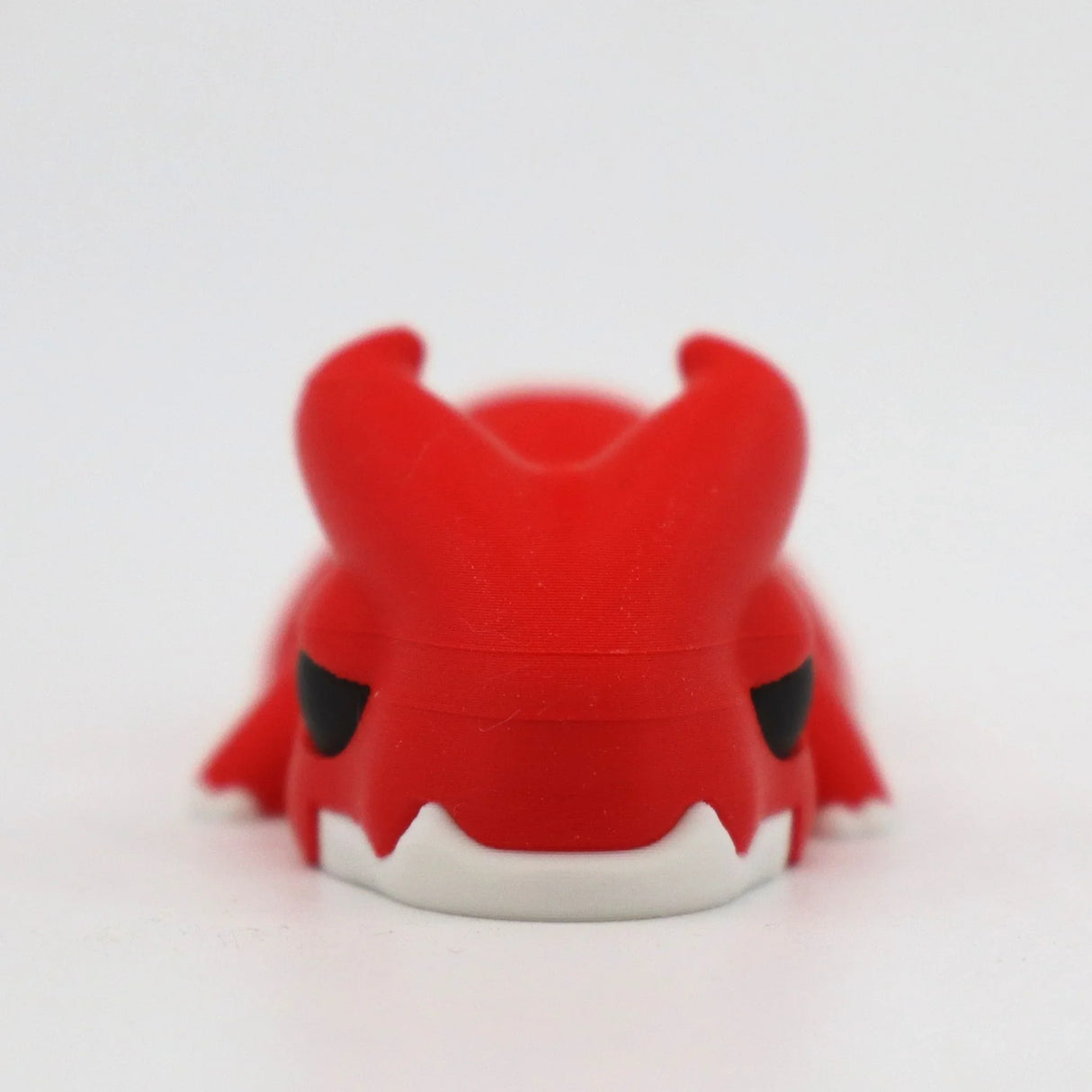 Red 3D printed dragon sensory toy with white fangs on a white background