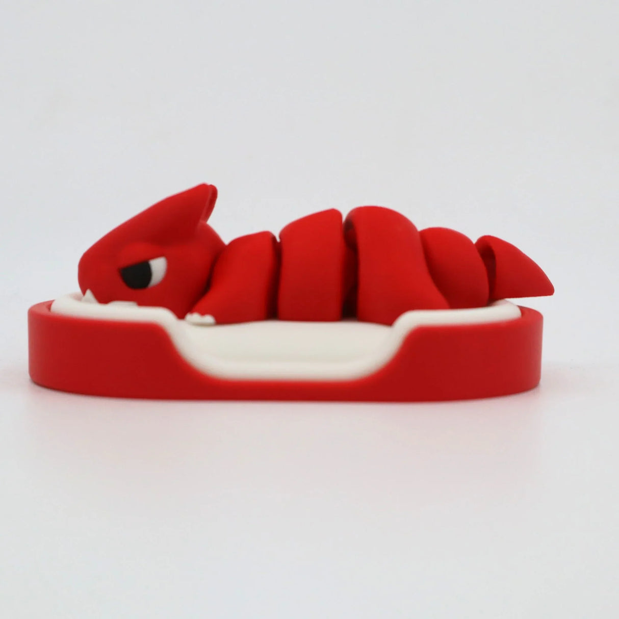 Red 3D printed sensory toy in the shape of a curled creature on a white base