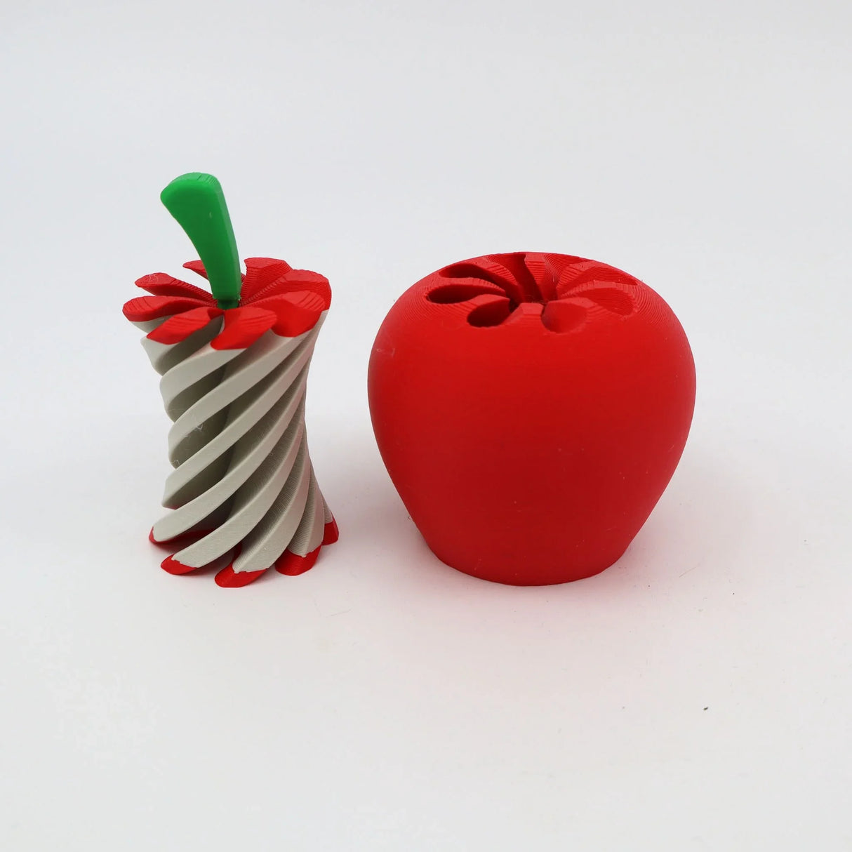 3D printed apple sensory toy with twistable core and bright red exterior on white background.