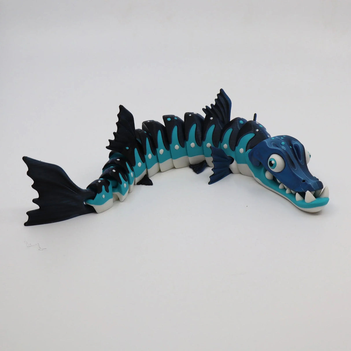 Blue and black articulated barracuda sensory toy with flexible segments on white background
