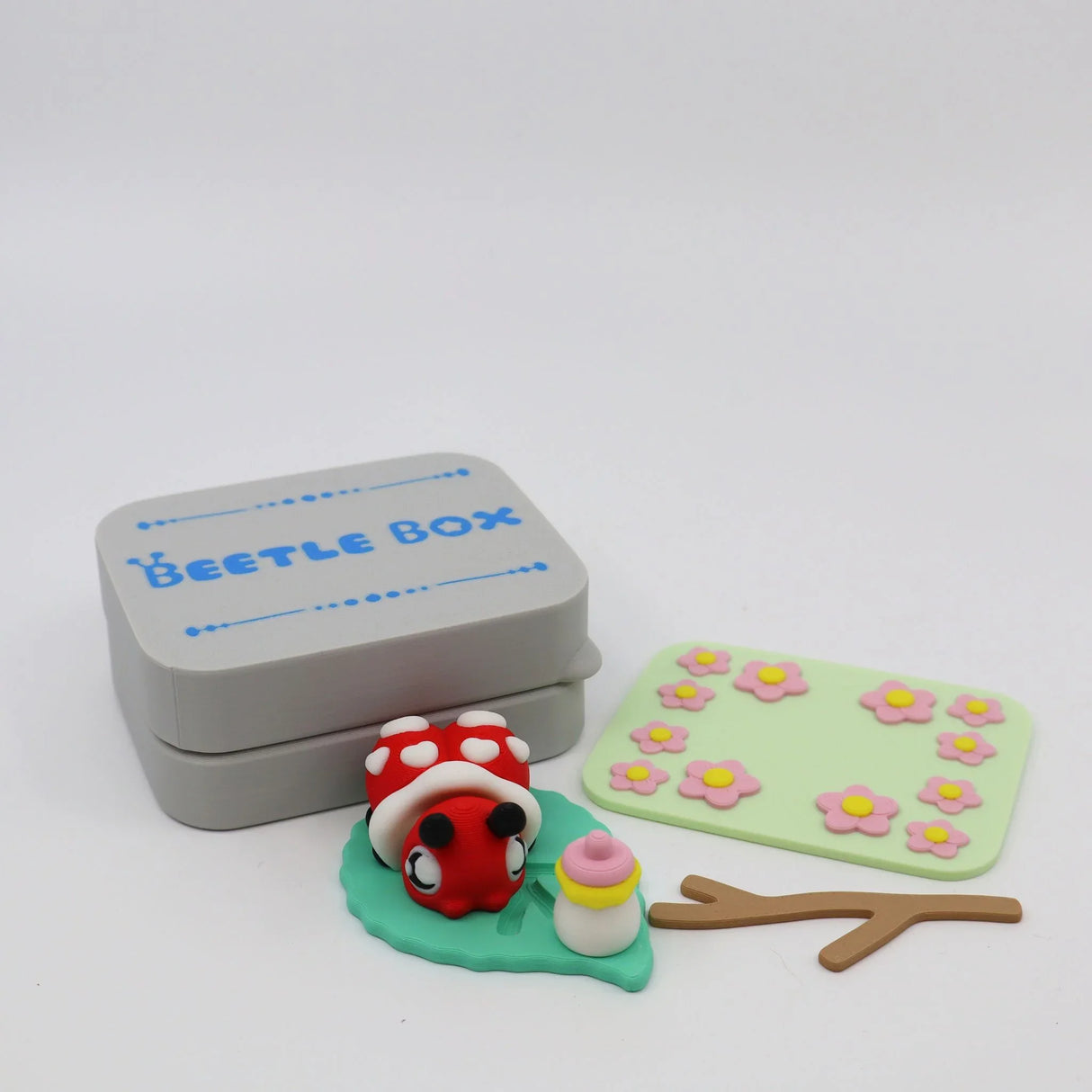 3D printed sensory toy set with ladybug, leaf, flowers, and gray Beetle Box container