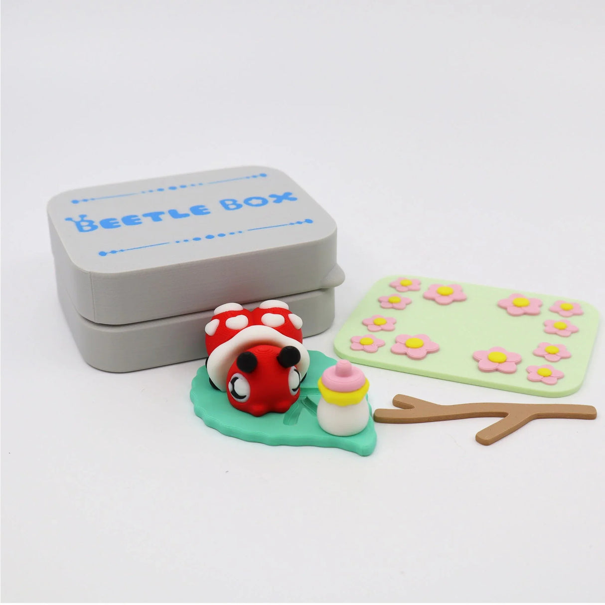 3D printed sensory toy set with ladybug, leaf, flowers, branch, and Beetle Box container