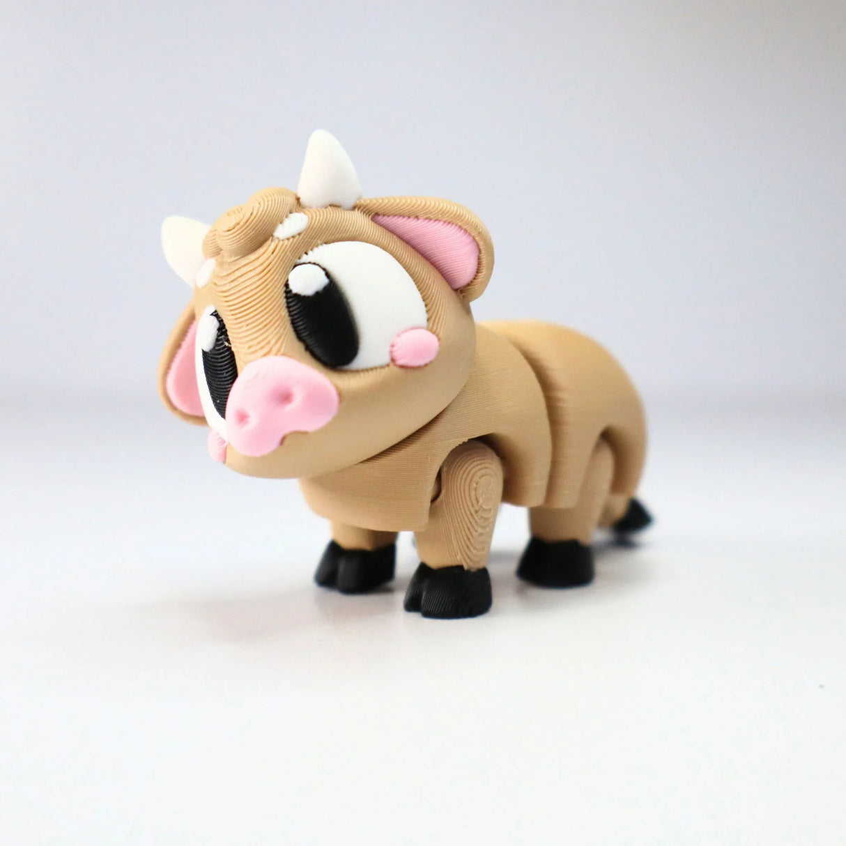 Cute 3D printed brown cow sensory toy with big eyes, pink nose, and black hooves on white background.