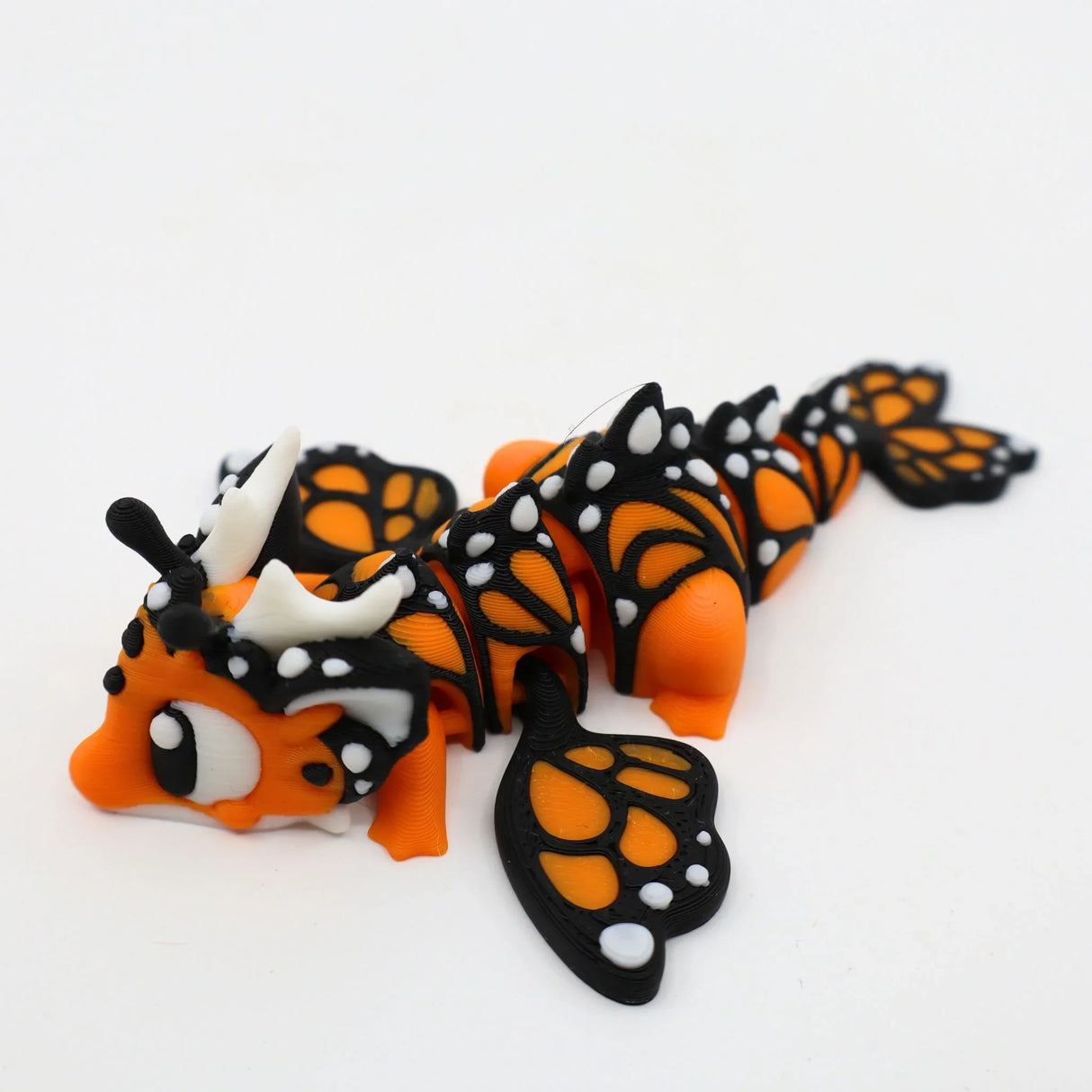 3D printed orange and black butterfly dragon sensory toy with flexible wings on white background