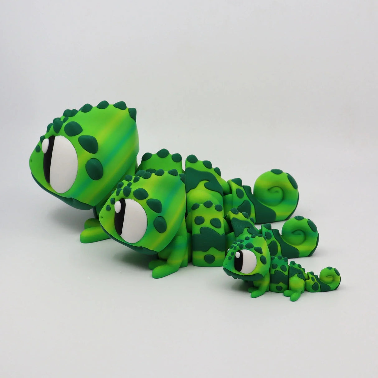 Three green 3D printed chameleon sensory toys in different sizes on white background