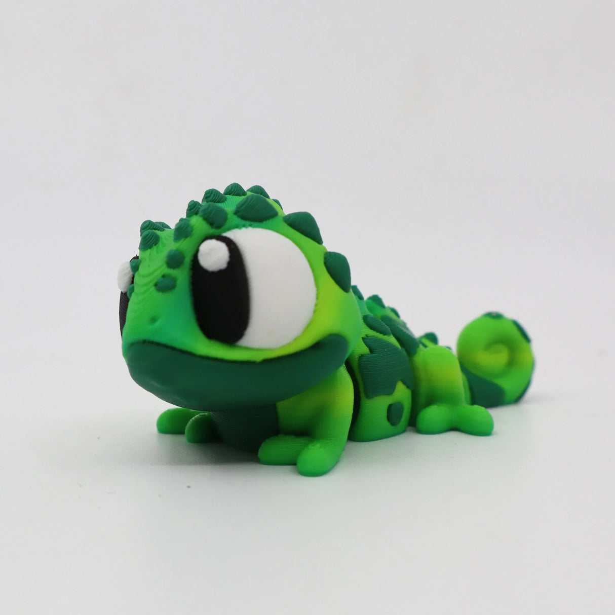 Green 3D printed chameleon sensory toy with large eyes on white background