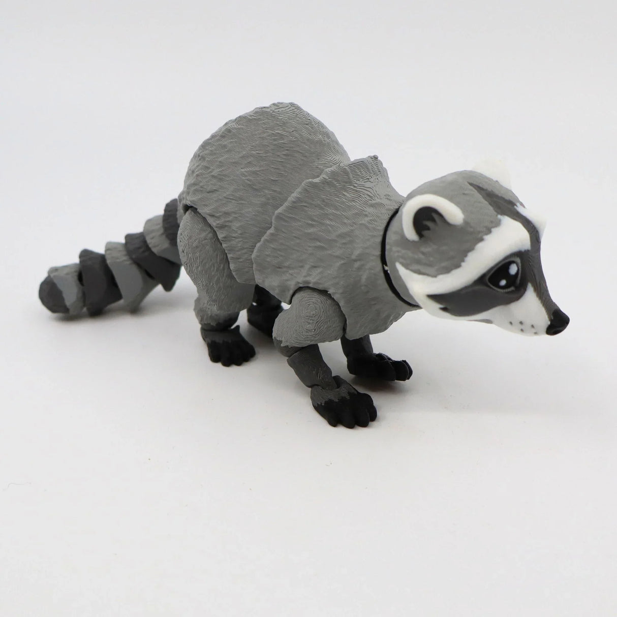 3D printed sensory raccoon toy with movable limbs on white background