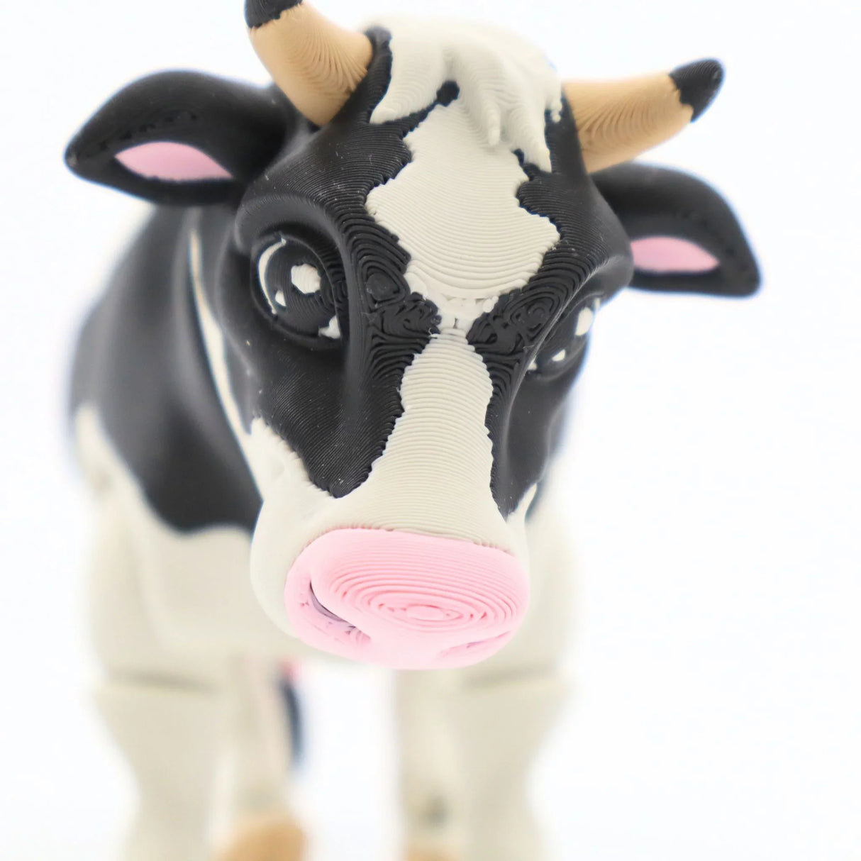 Black and white 3D printed cow sensory toy with pink nose on white background