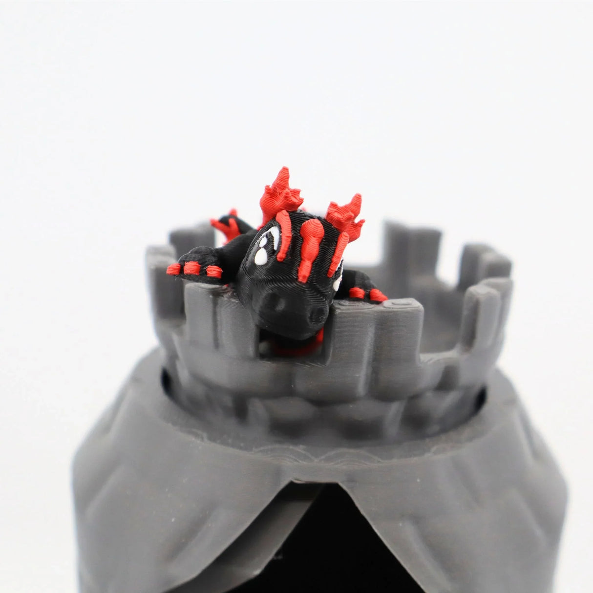 3D printed black and red dragon toy atop a gray castle sensory toy