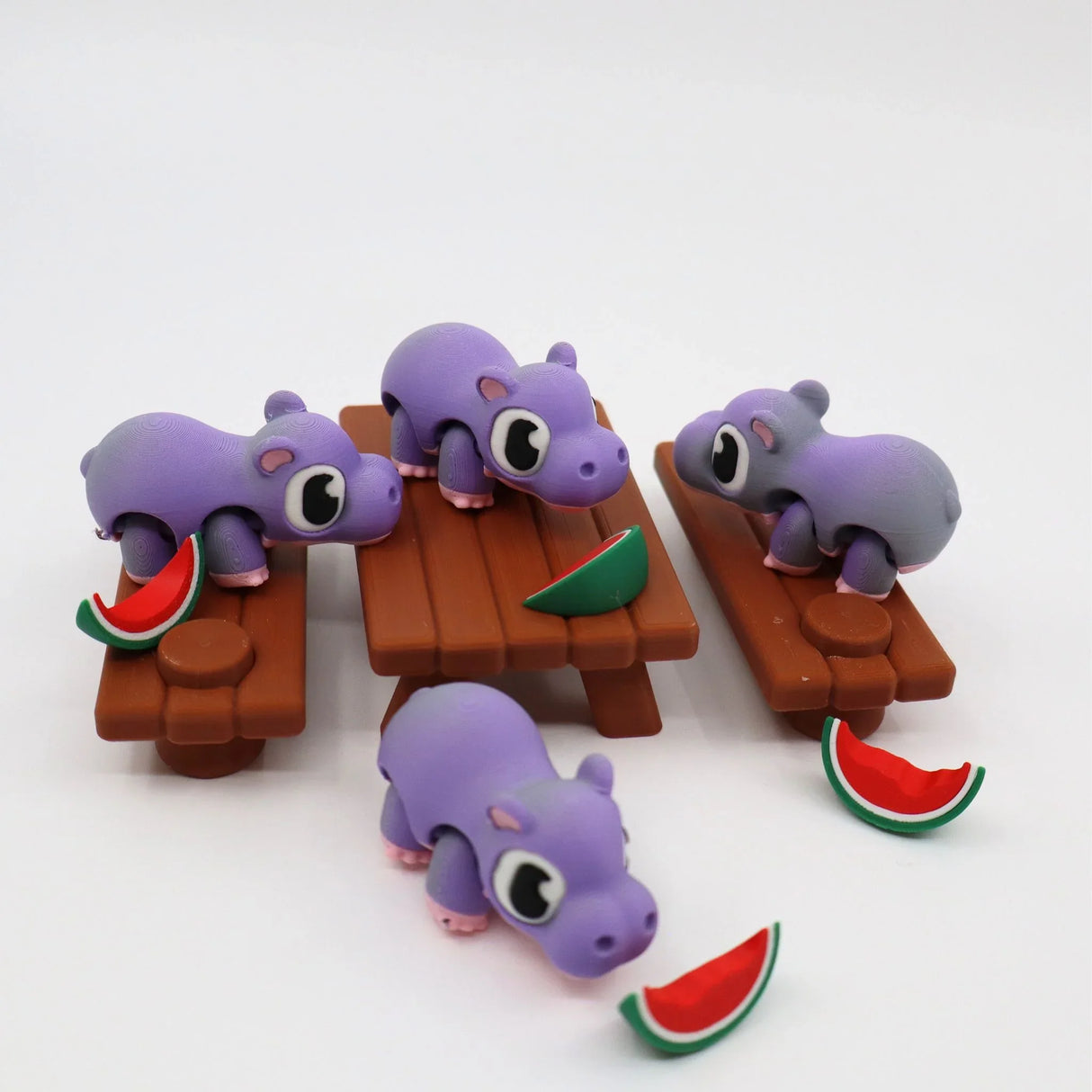 Purple 3D printed hippo sensory toys with watermelon slices on picnic tables