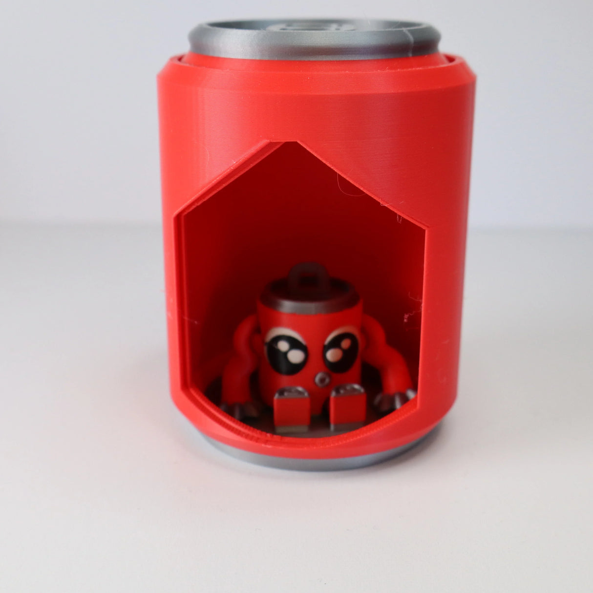 Red 3D printed sensory toy shaped like a can with a cute octopus figure inside