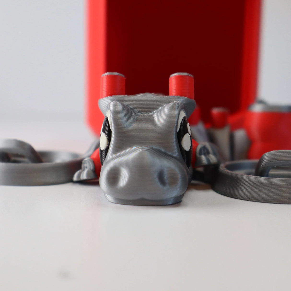 3D printed gray sensory toy shaped like a cartoon animal with red accents on a white surface