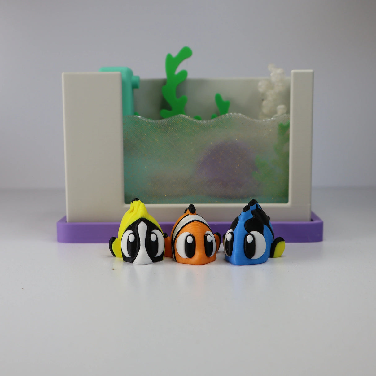 Colorful 3D printed sensory toy fish in front of a small toy aquarium