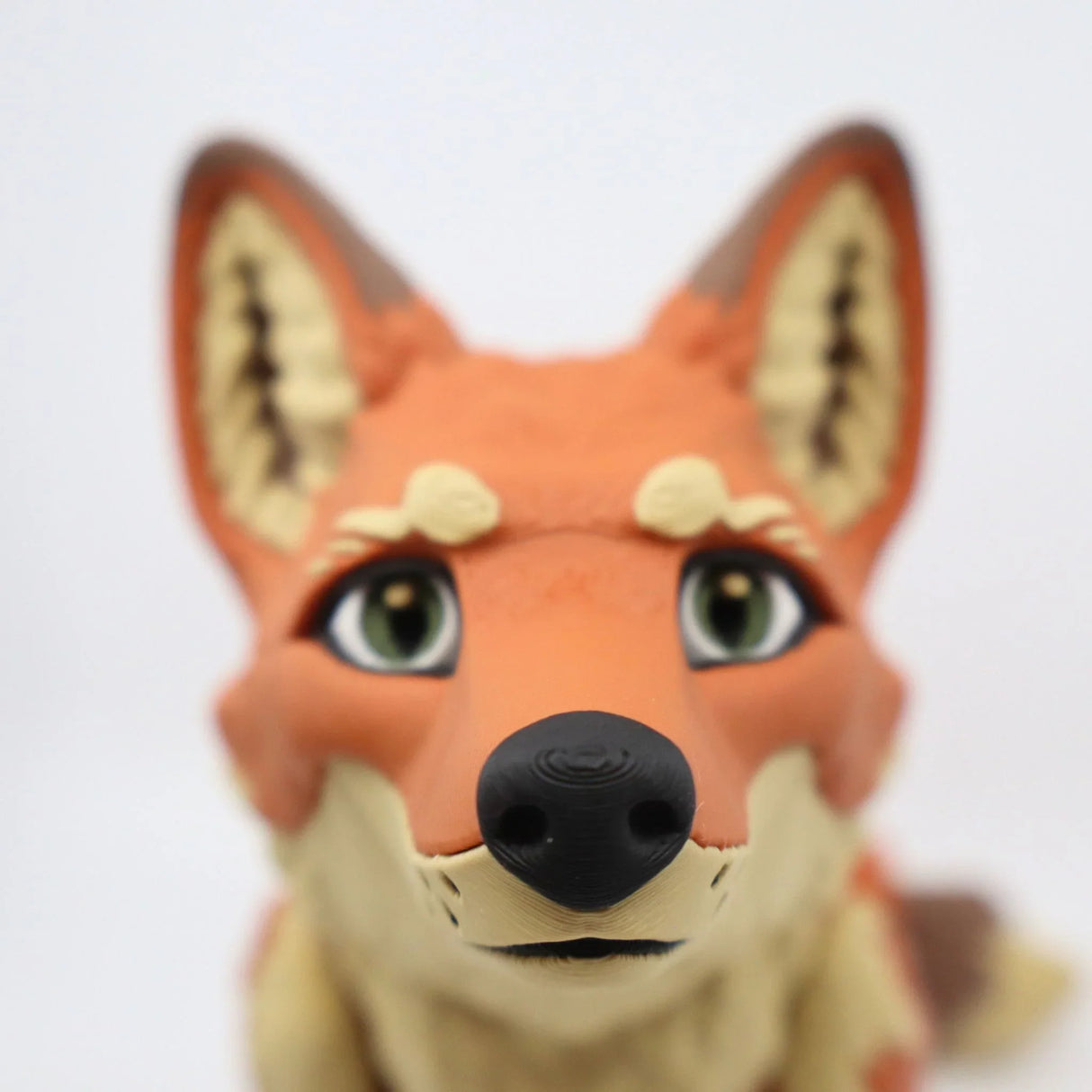 Close-up of a 3D printed orange fox sensory toy with green eyes and detailed facial features