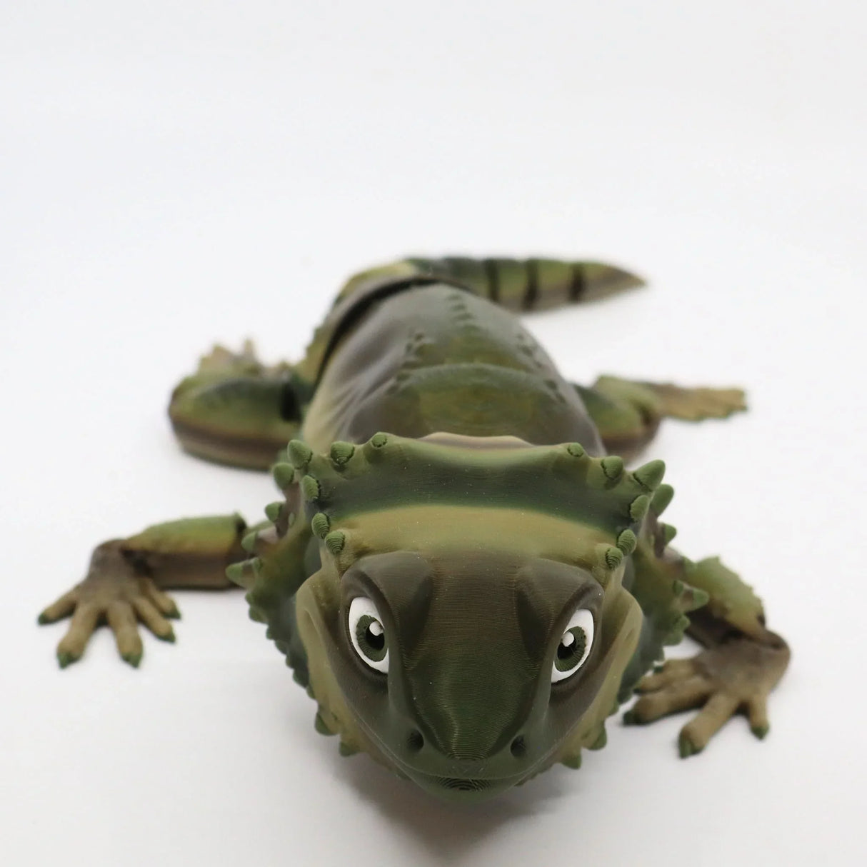 3D printed green sensory toy lizard with textured back and large eyes on white background