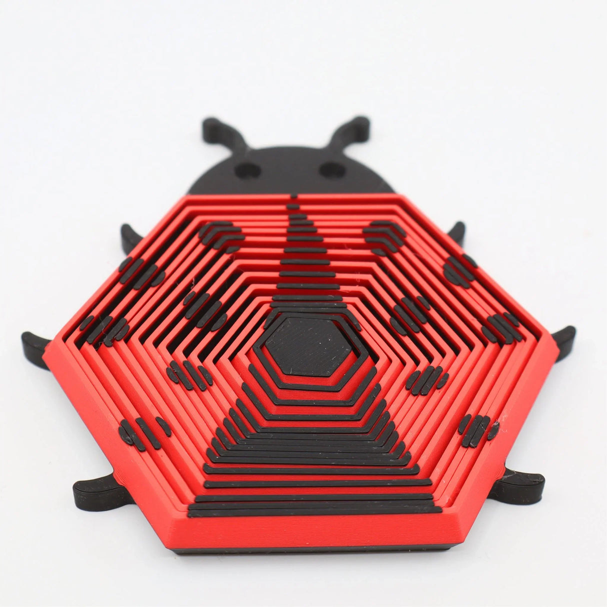 Red and black hexagonal ladybug-shaped 3D printed sensory fidget toy on white background