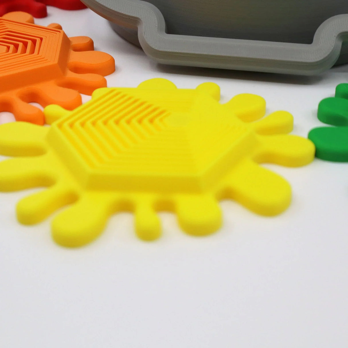 Colorful 3D printed sensory fidget toys shaped like paint splatters on white background