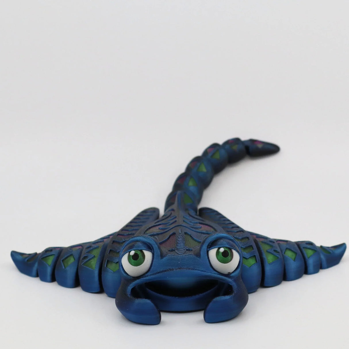 Blue 3D printed stingray sensory toy with green eyes, textured body, and flexible tail