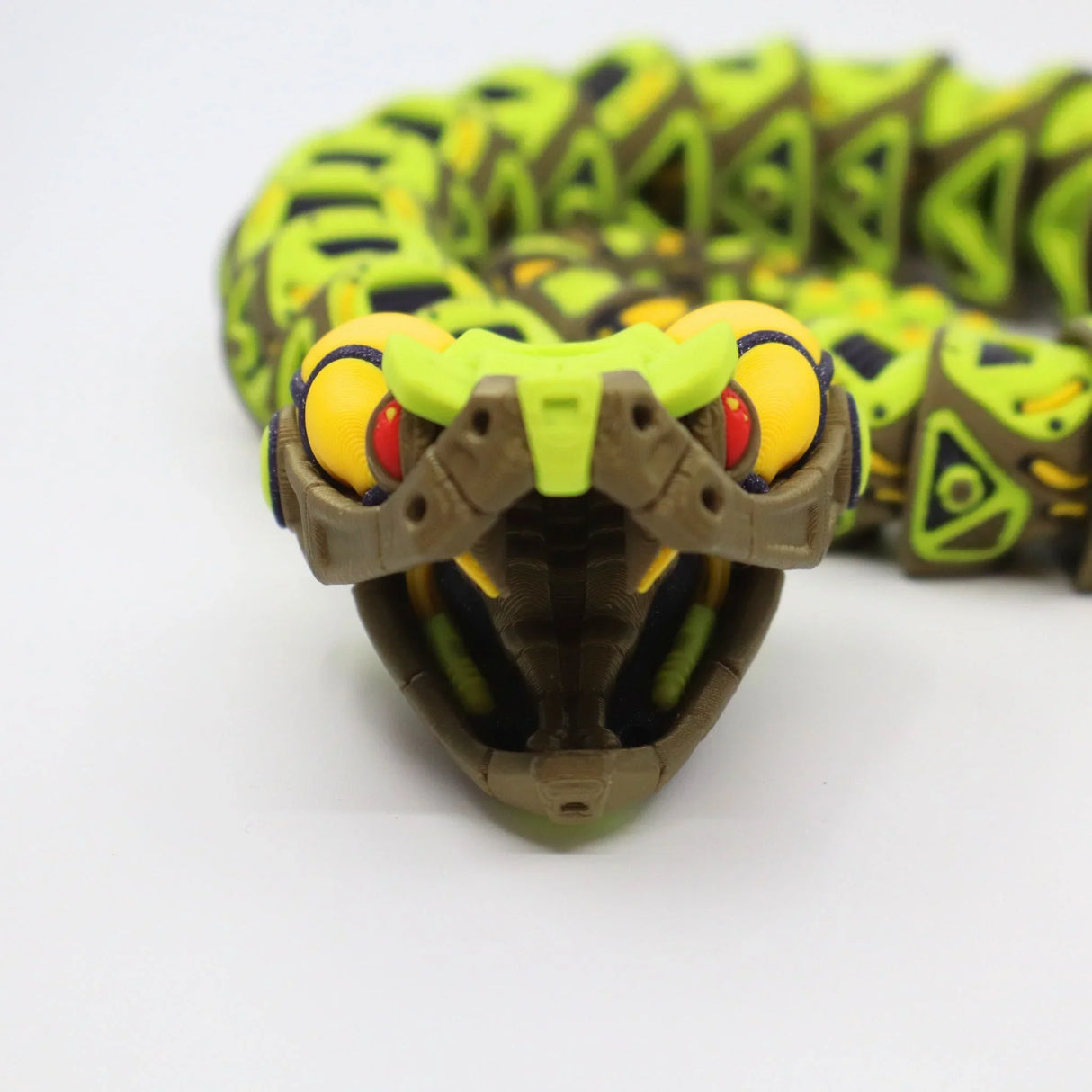 3D printed sensory toy snake with green, yellow, and brown segments on white background