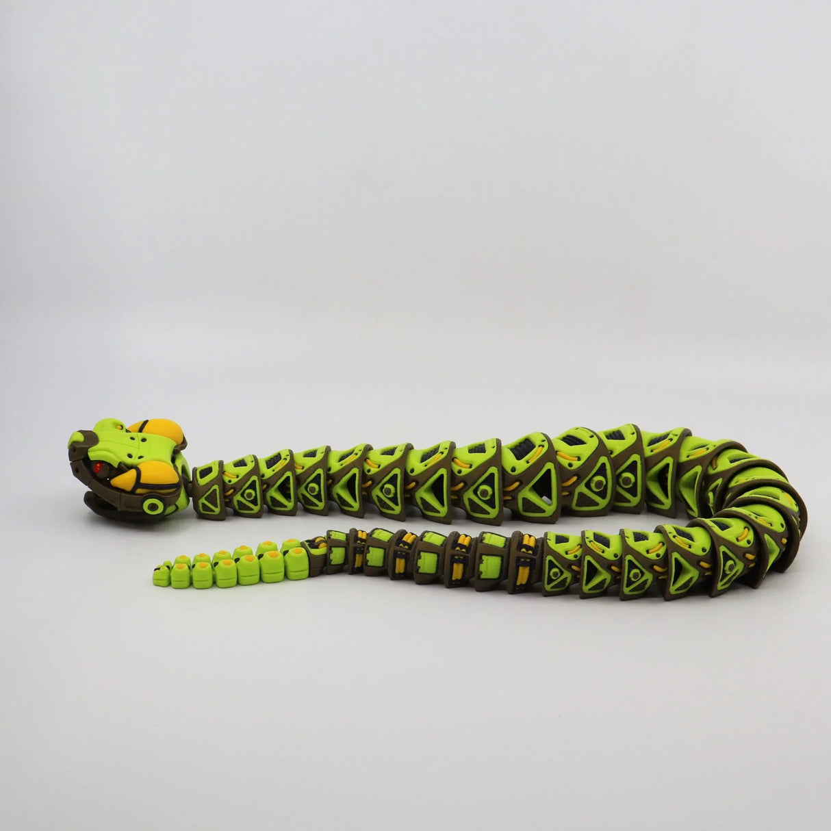 Green and yellow 3D printed sensory snake toy with jointed body on plain background