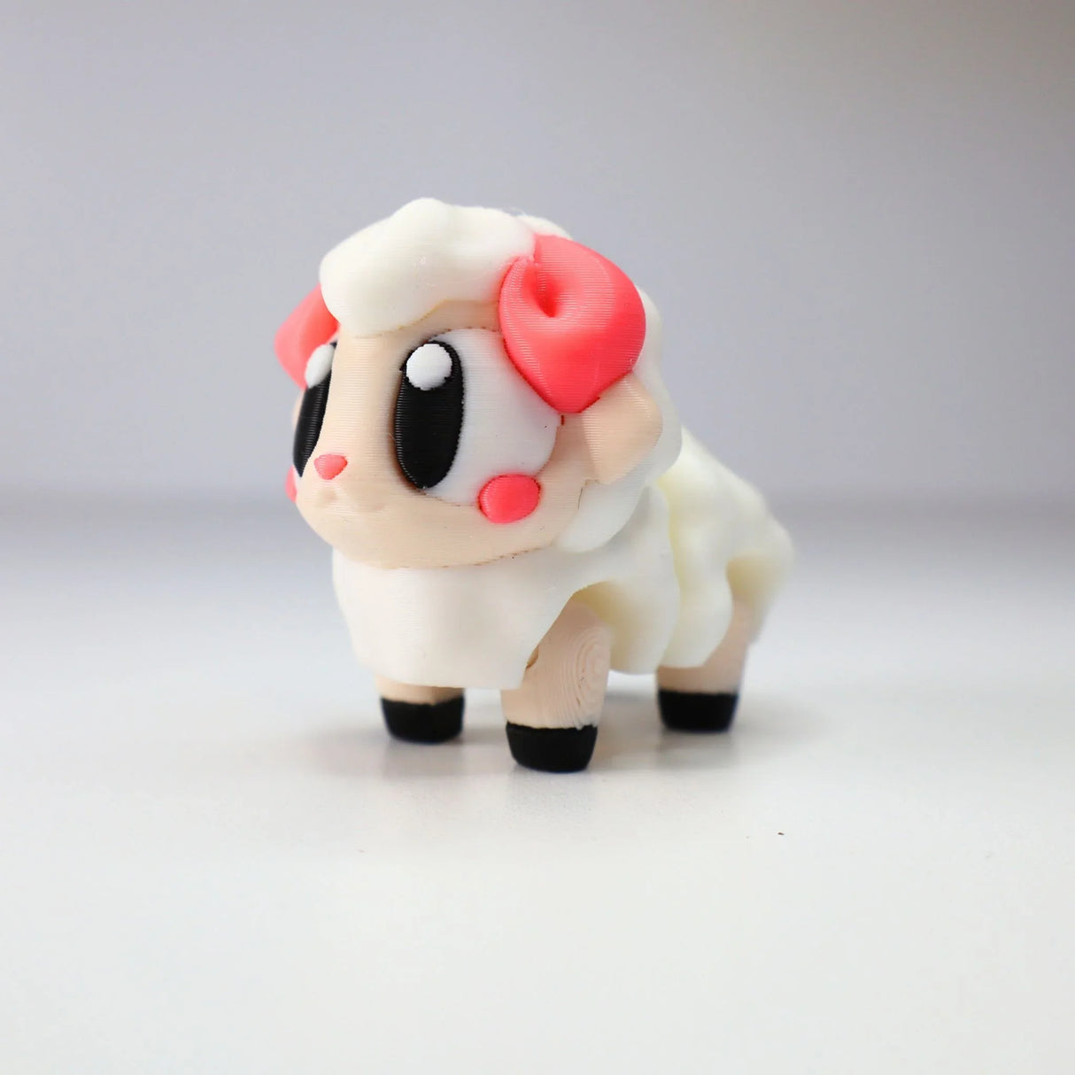 Cute 3D printed sheep sensory toy with pink ears, big eyes, and white body on white background
