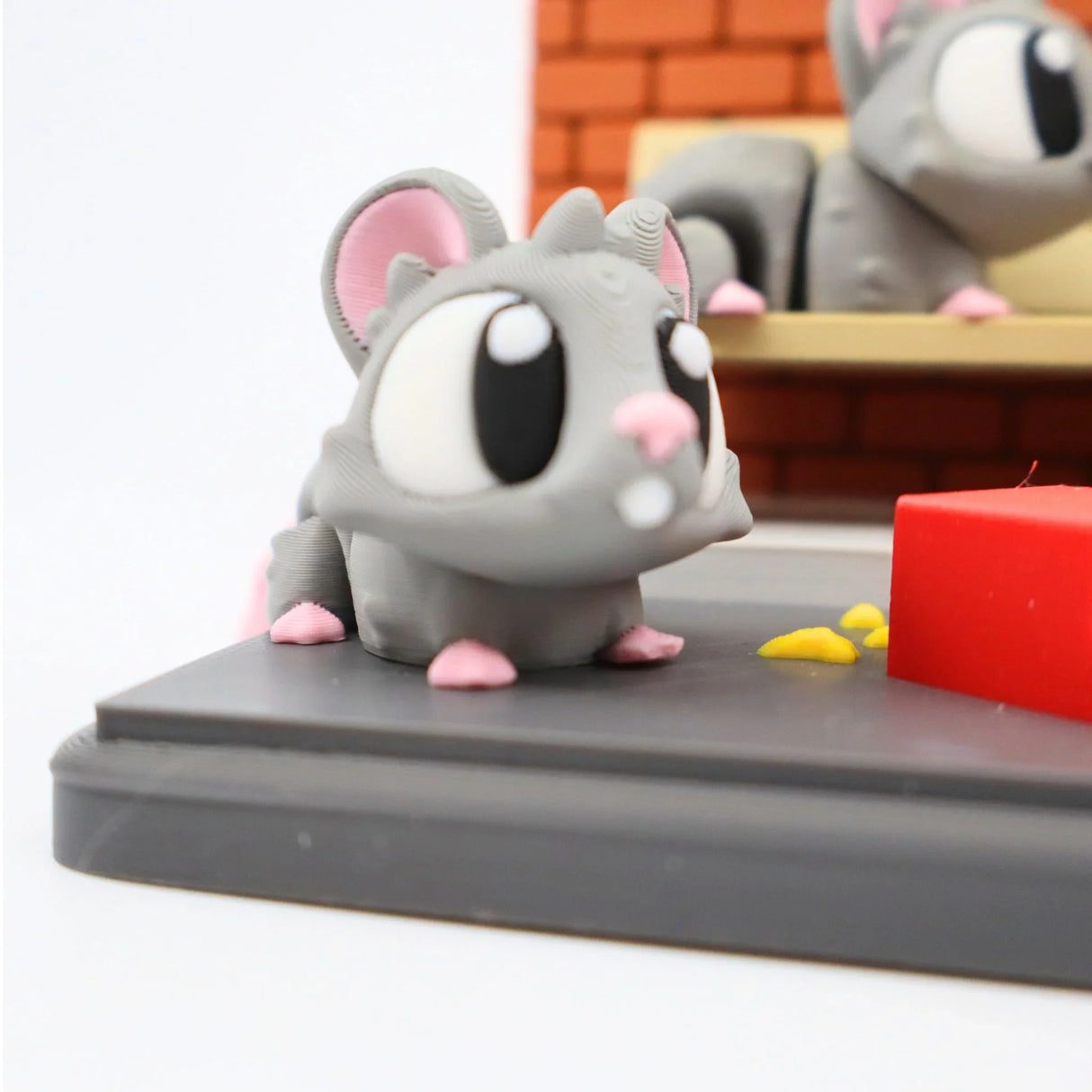 Cute 3D printed grey sensory toy rat with large eyes on miniature subway scene