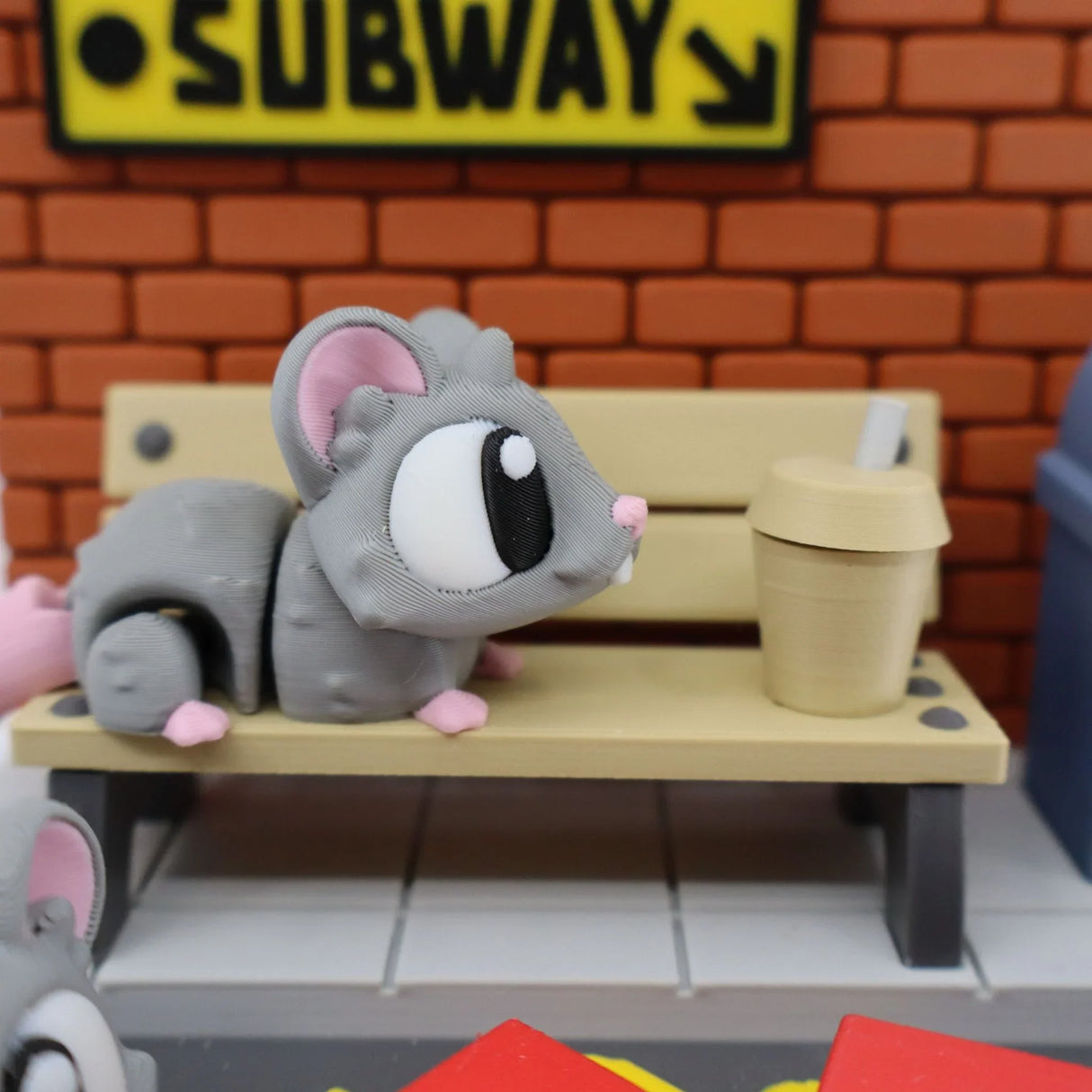 3D printed sensory toy mouse on subway bench with coffee cup and brick wall background