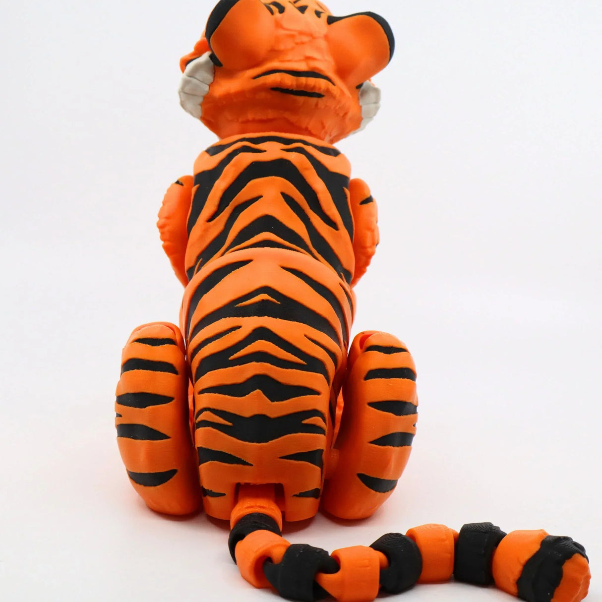 3D printed orange and black tiger sensory toy with flexible tail on white background