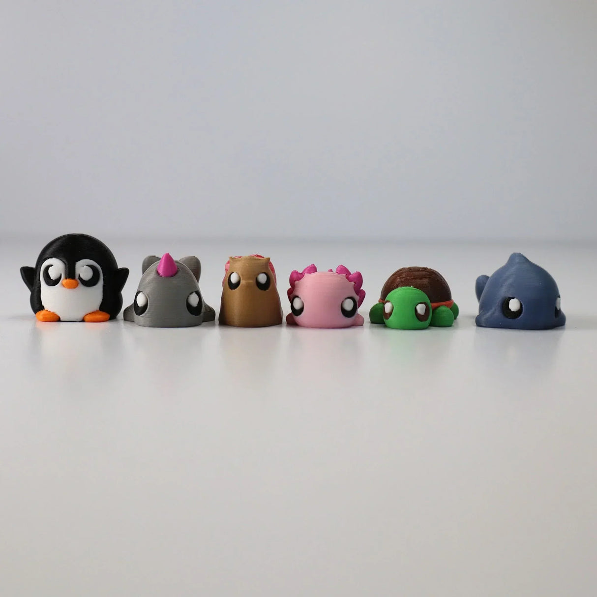 Colorful 3D printed sensory animal toys lined up on a white background