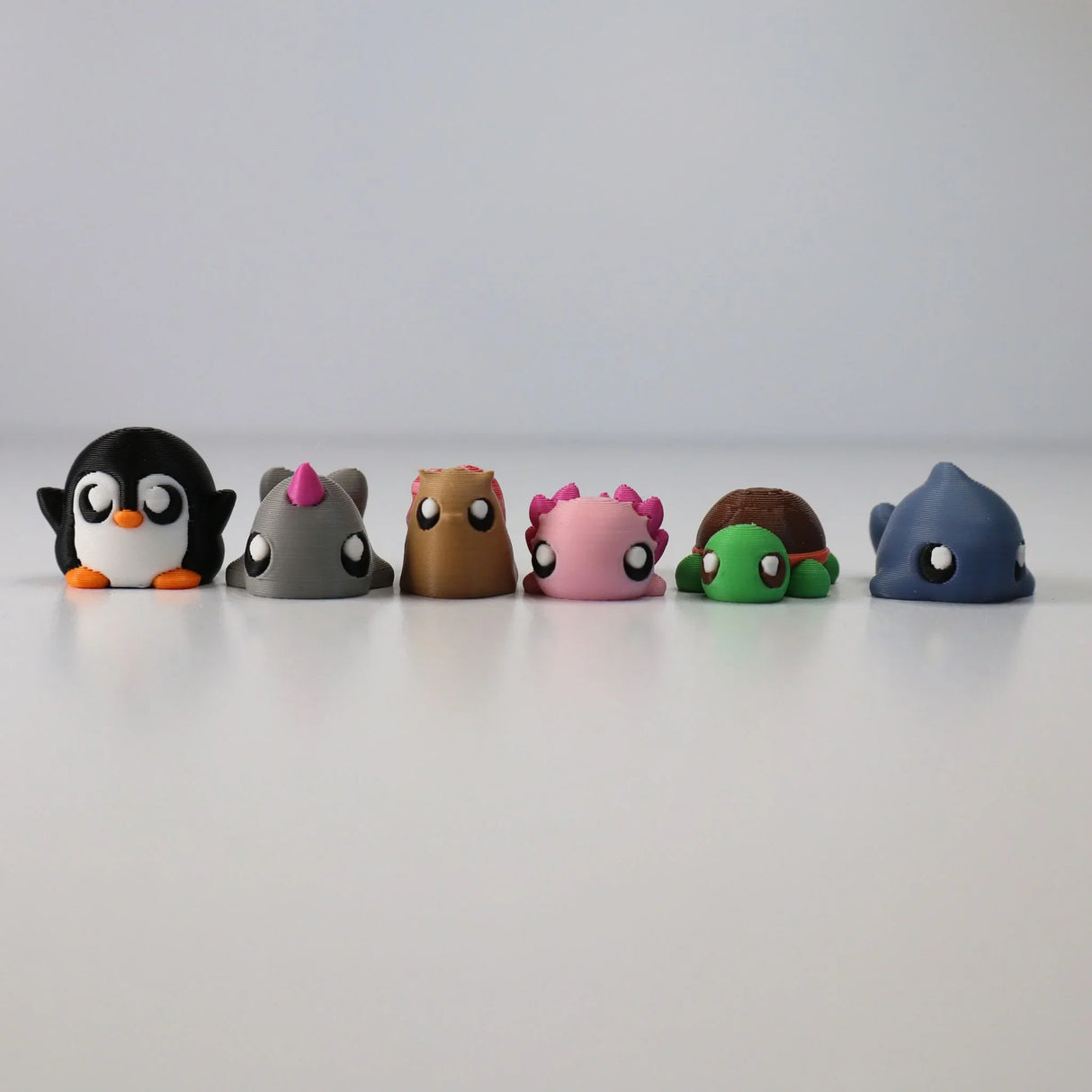 Colorful 3D printed animal sensory toys arranged in a row on a white surface.
