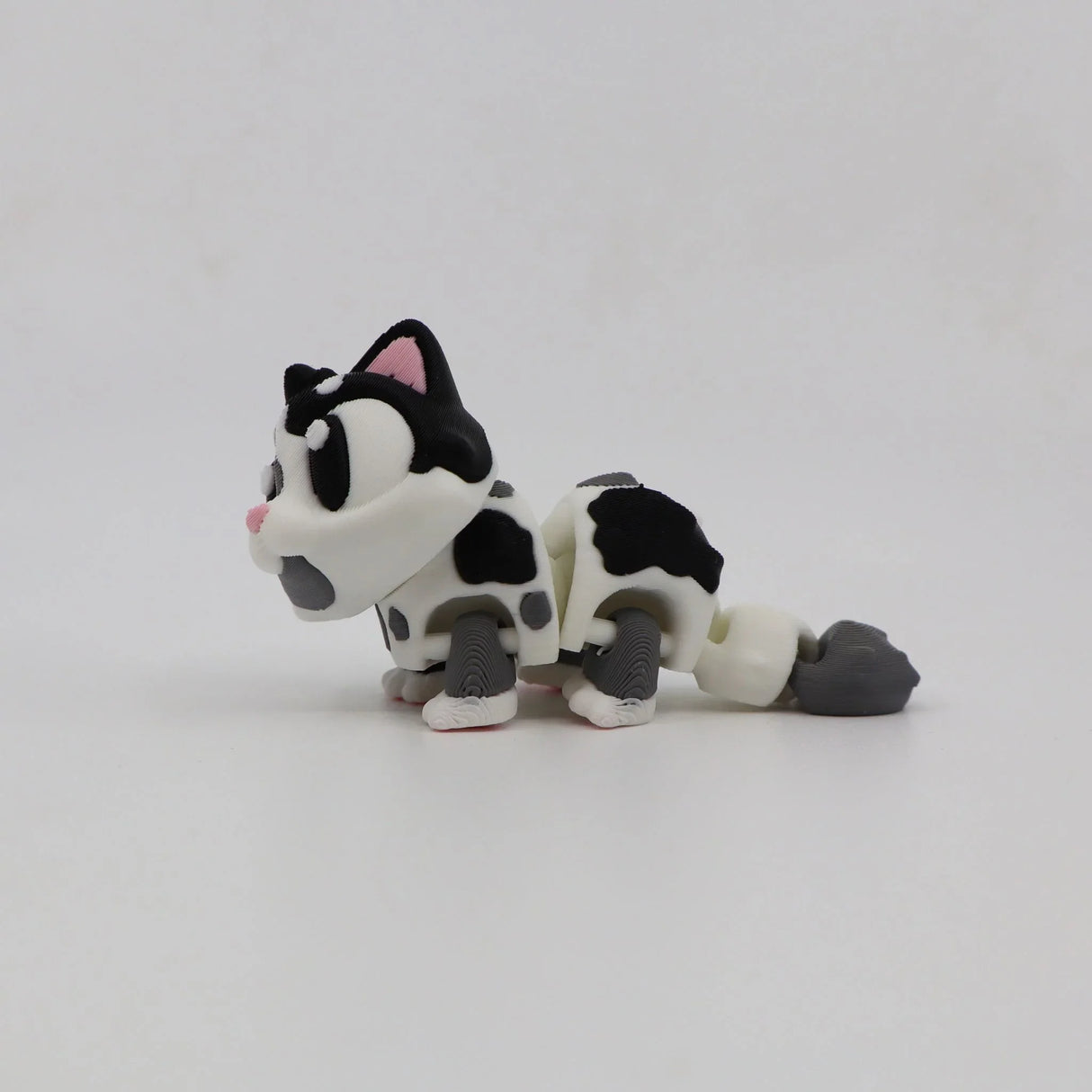 3D printed sensory toy cat with black and white spots on a plain white background