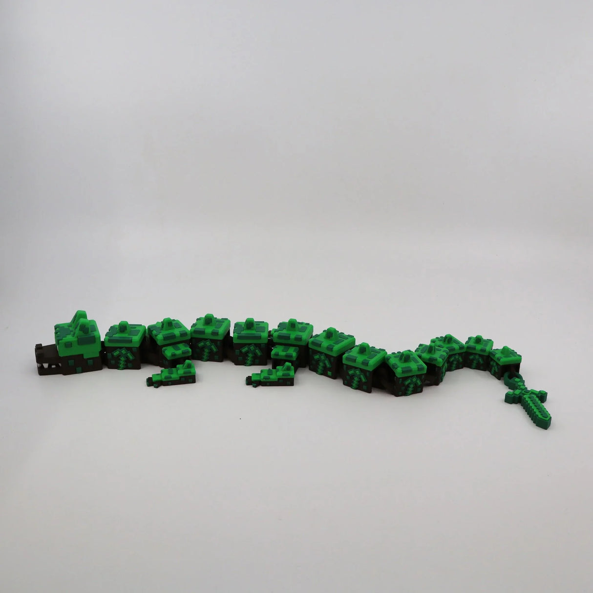 Pixelated green and brown 3D printed flexi dragon toy for sensory play and fidgeting