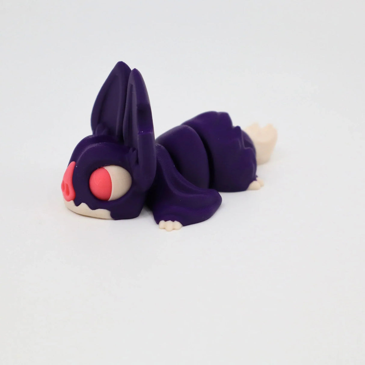 Purple 3D printed sensory toy animal with large ears and pink eyes on white background