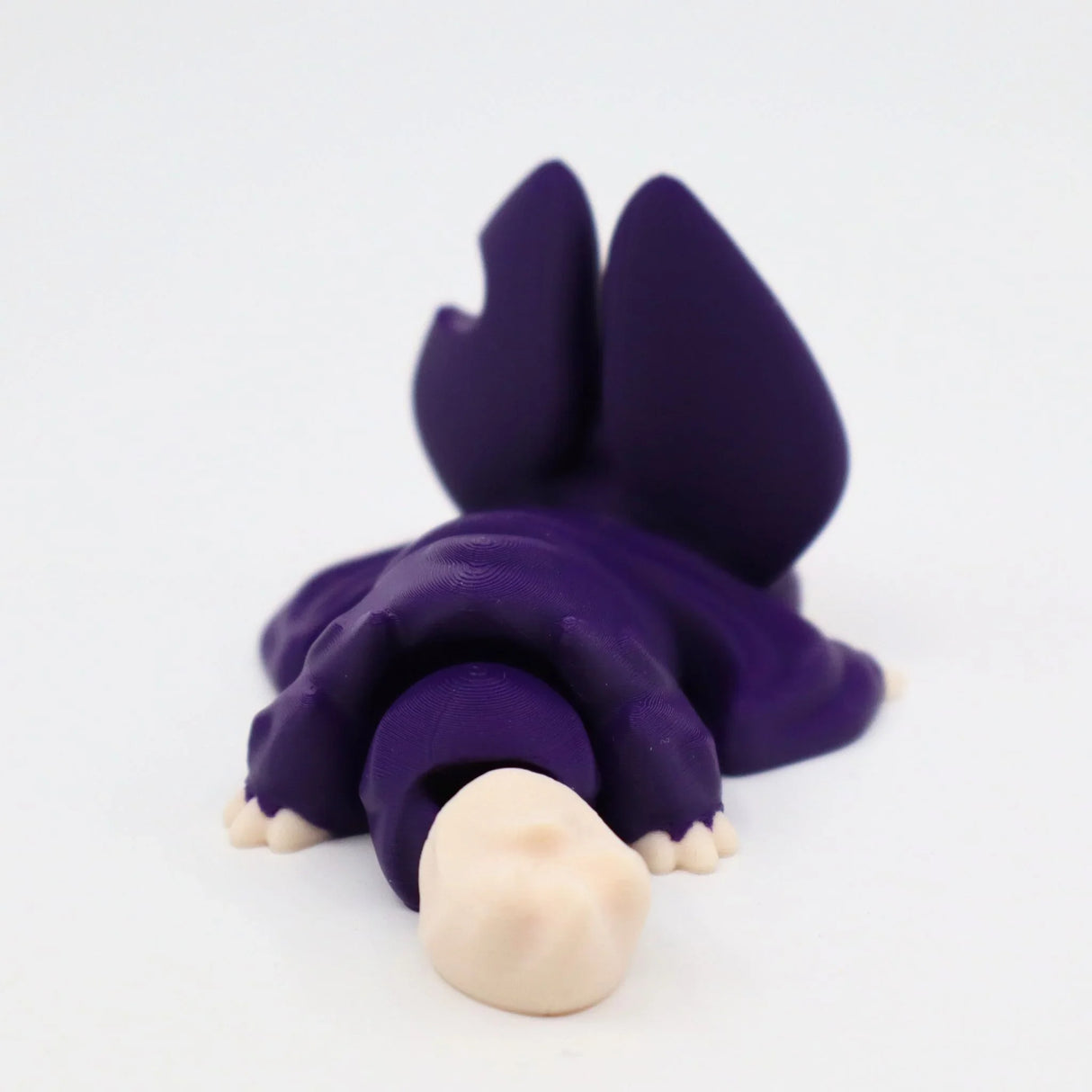 Purple 3D printed sensory toy shaped like a lizard with beige face on white background