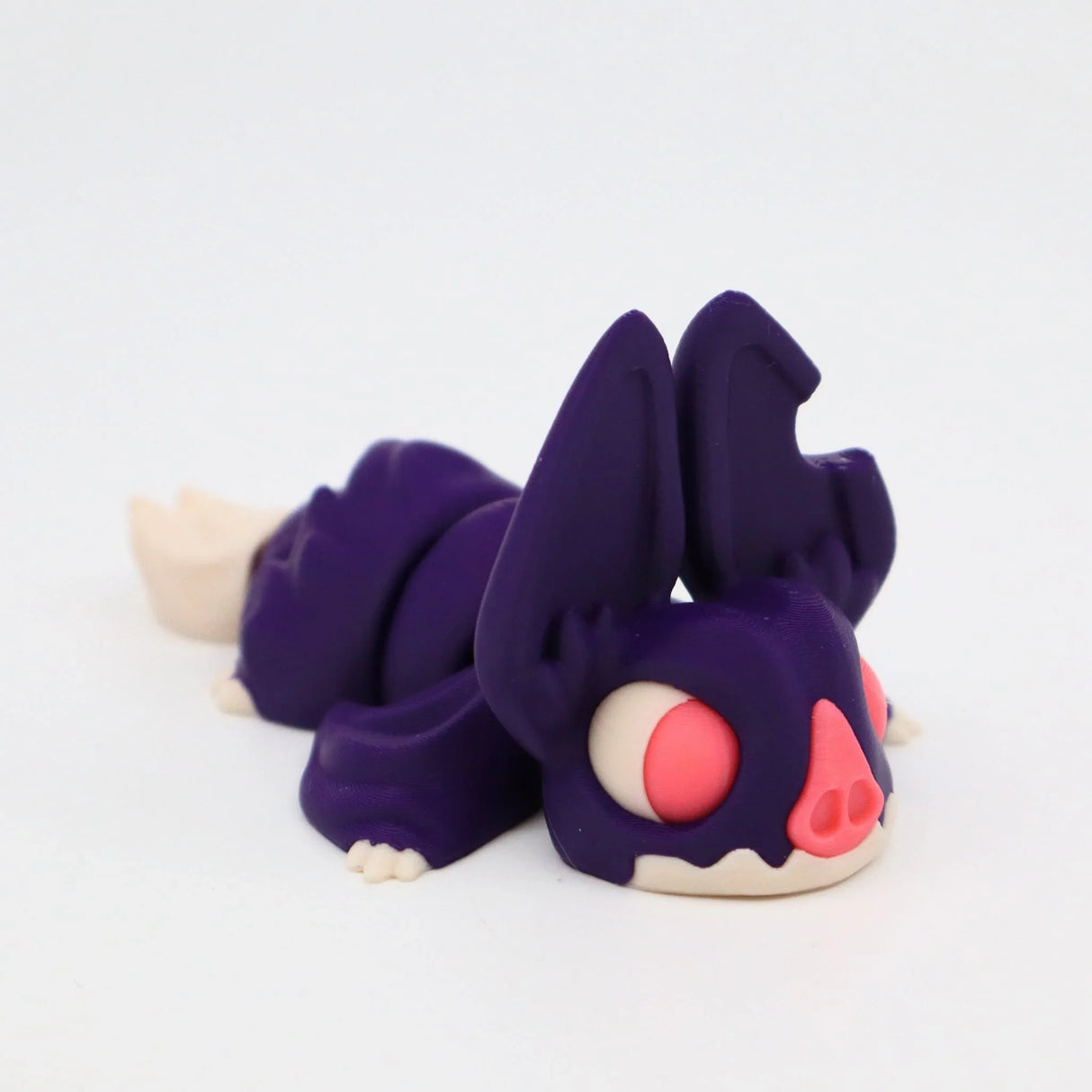 Purple 3D printed sensory toy animal with large ears and pink eyes, on white background