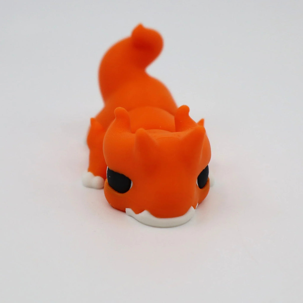 Orange 3D printed flexi dragon fidget toy for sensory play, featuring black eyes and white accents