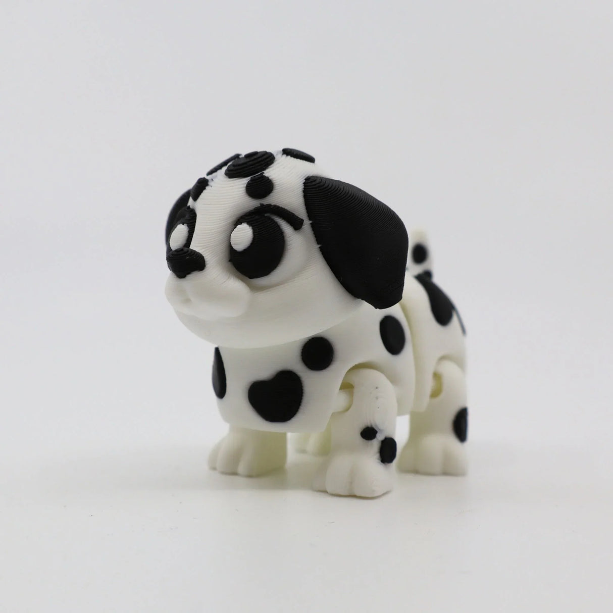 3D printed Dalmatian puppy fidget toy with black spots and flexible joints for sensory play