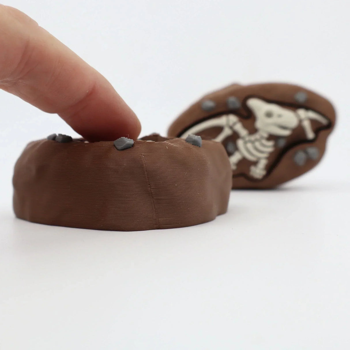 3D printed dinosaur fossil sensory toy with textured surface and embedded stones