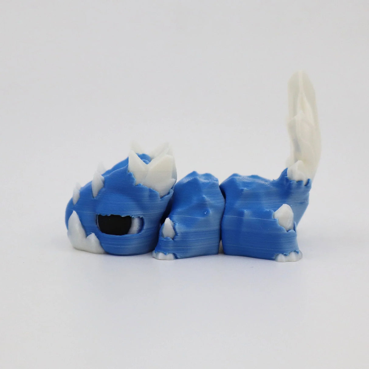 Blue and white 3D printed sensory toy dragon with spikes on a white background
