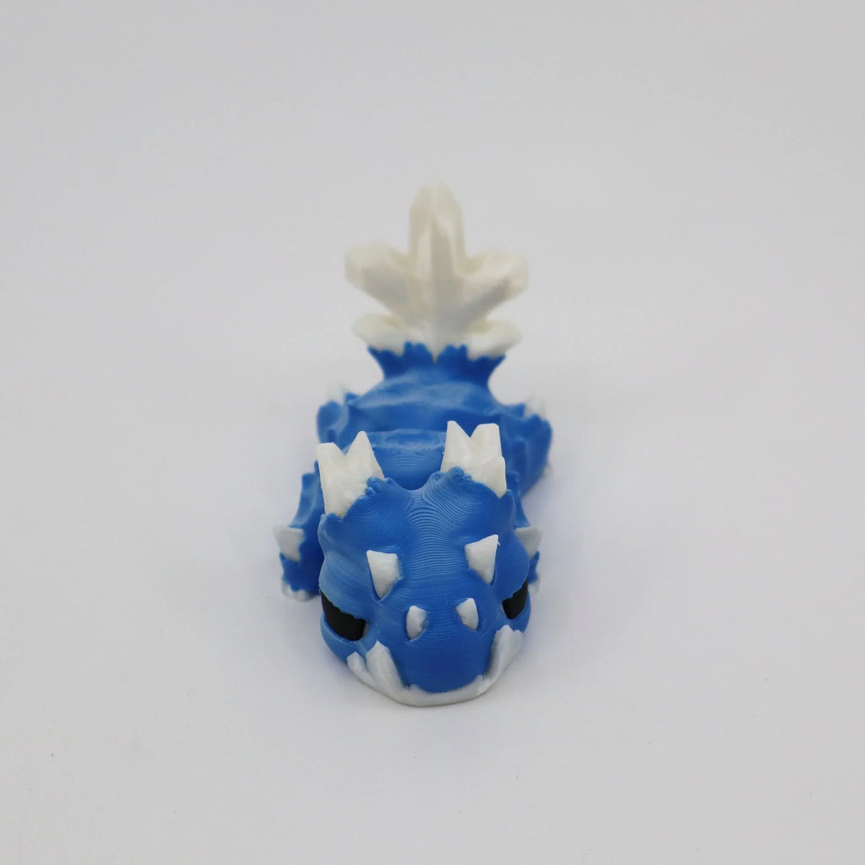 Blue and white 3D printed sensory toy dragon with articulated body on white background