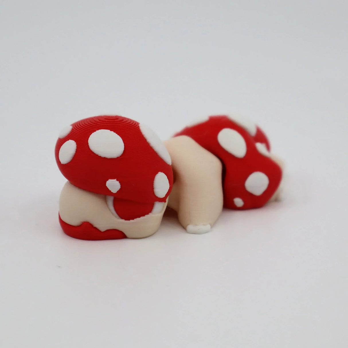 3D printed red and white polka dot mushroom sensory toy on white background