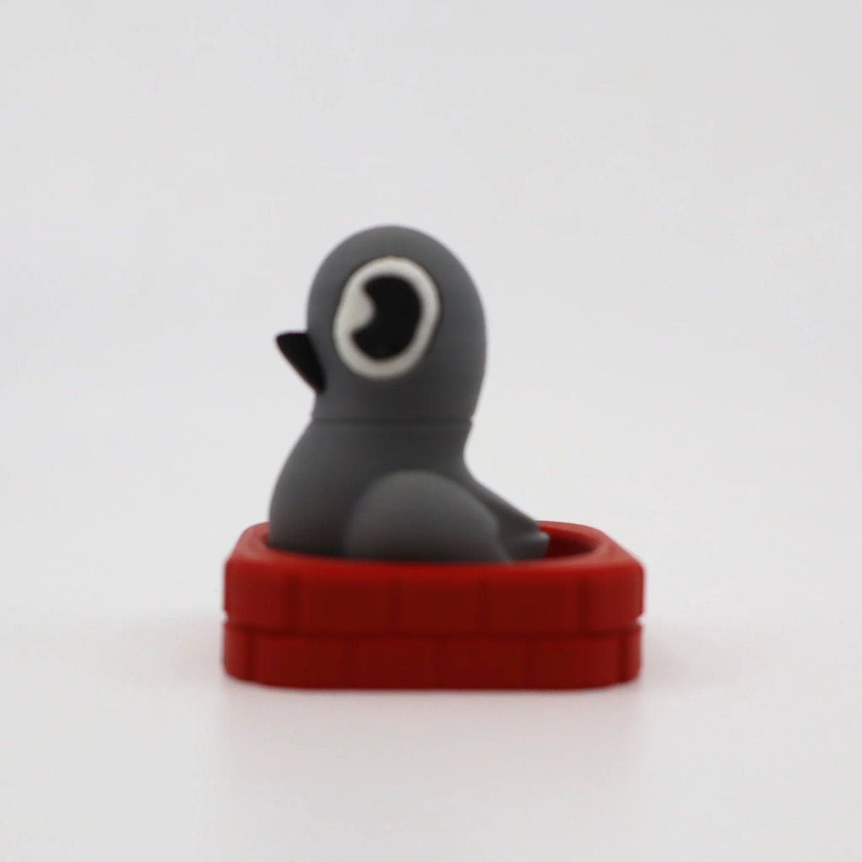 Gray penguin sensory fidget toy in red brick base, 3D printed for tactile play