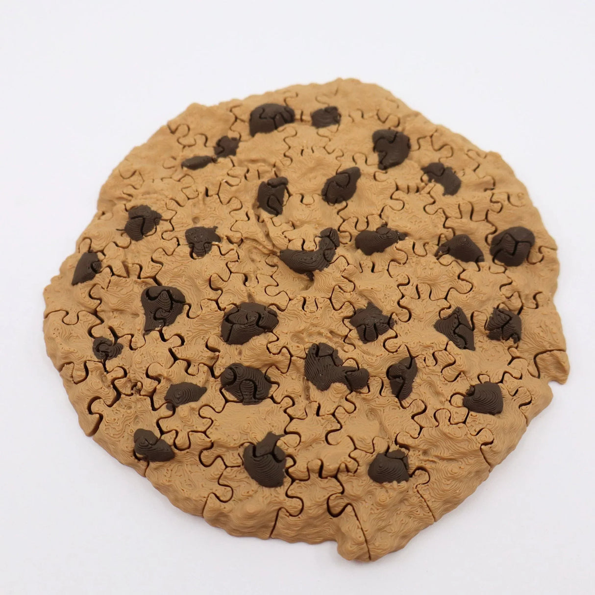 3D printed chocolate chip cookie puzzle with textured surface on white background