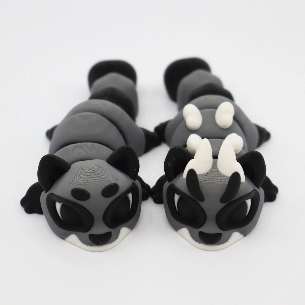 Two gray and black 3D printed sensory animal fidget toys with white horns on a white background