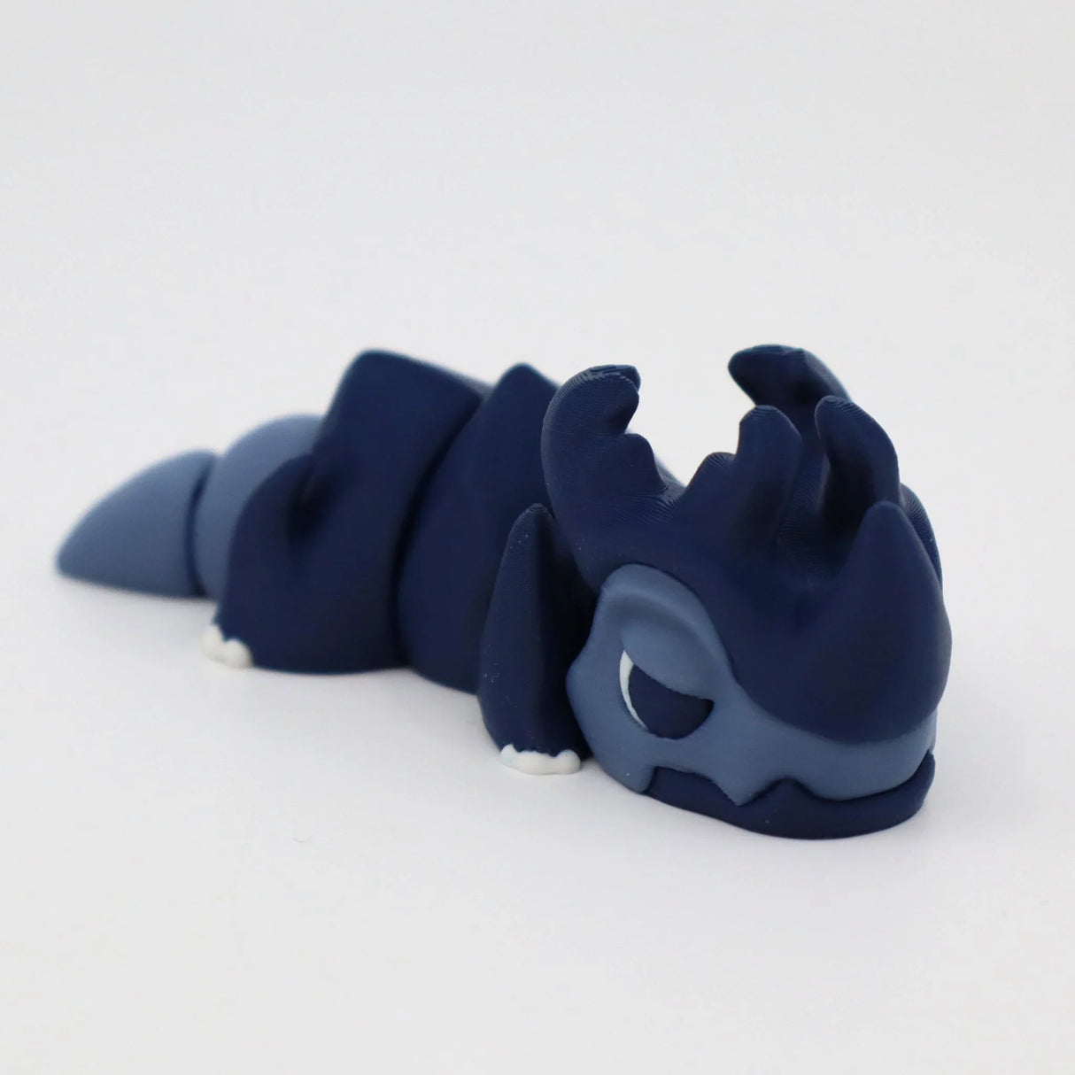 Blue 3D printed sensory fidget toy shaped like a dragon, resting on a white background