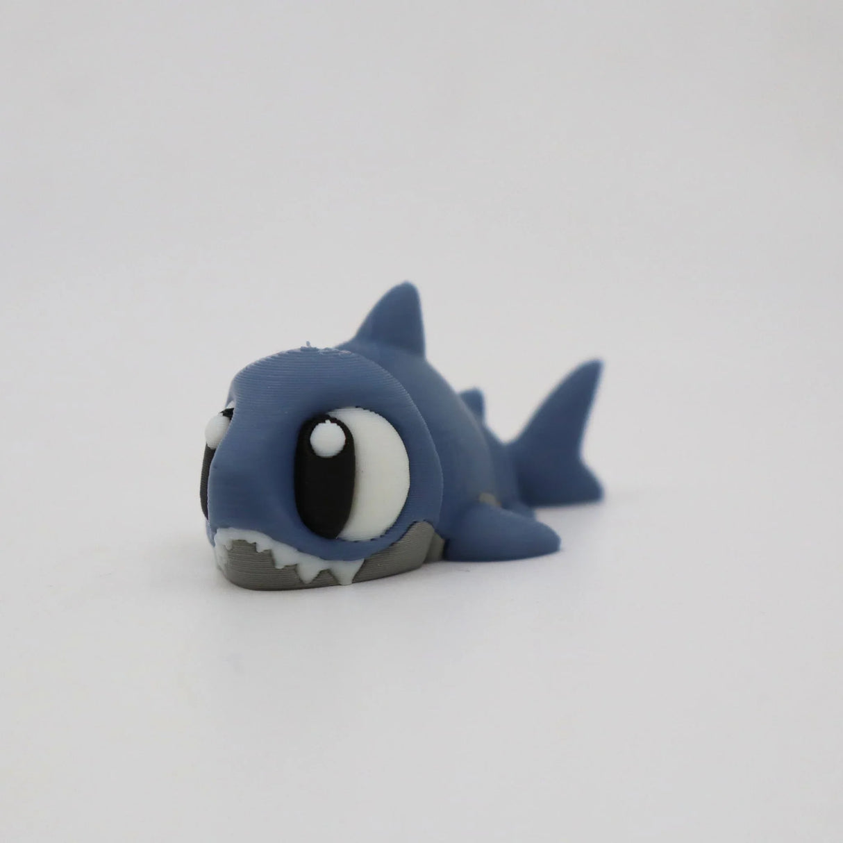 Cute 3D printed shark sensory toy with big eyes on a plain white background