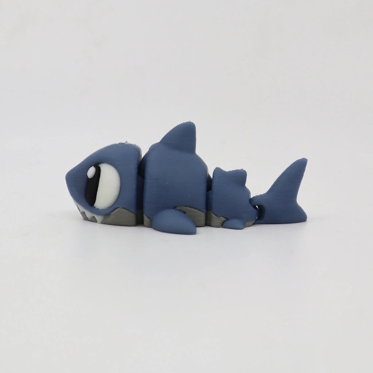 Blue 3D printed shark fidget toy with movable segments on a white background.