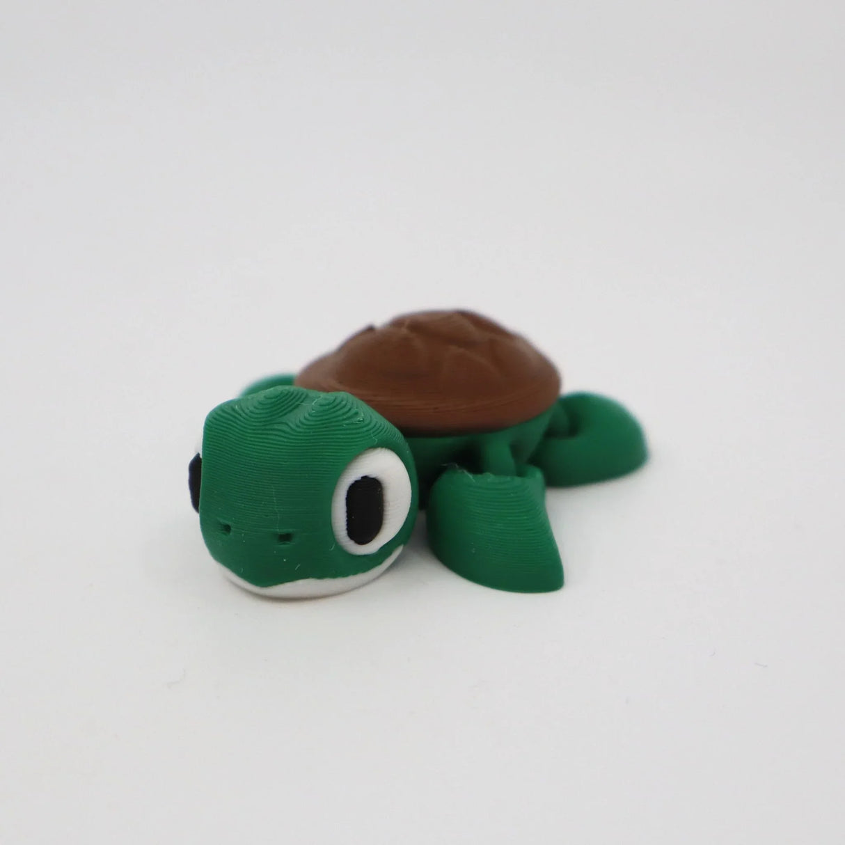 3D printed green and brown turtle sensory toy on a plain white background