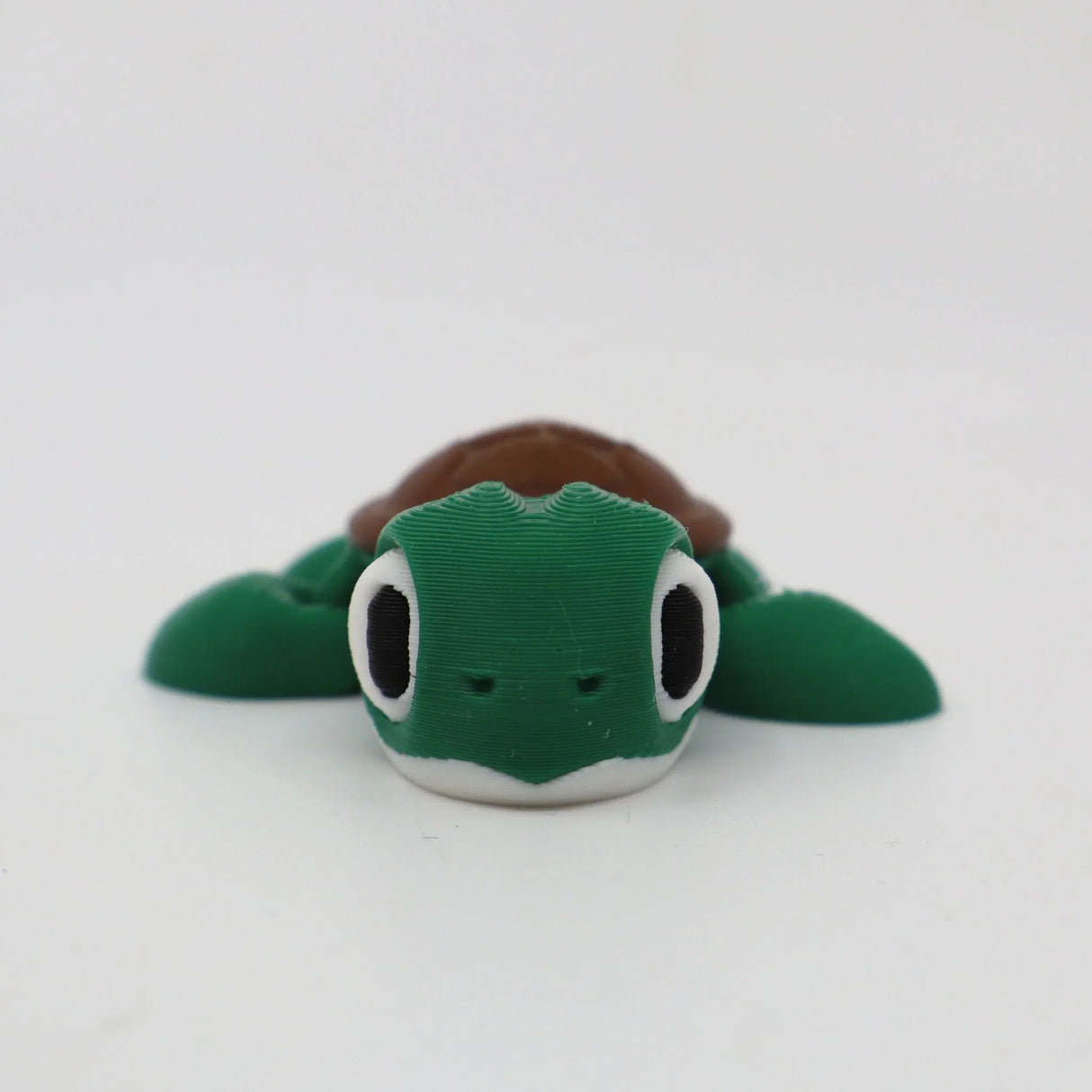 Green 3D printed turtle sensory toy with large eyes on white background