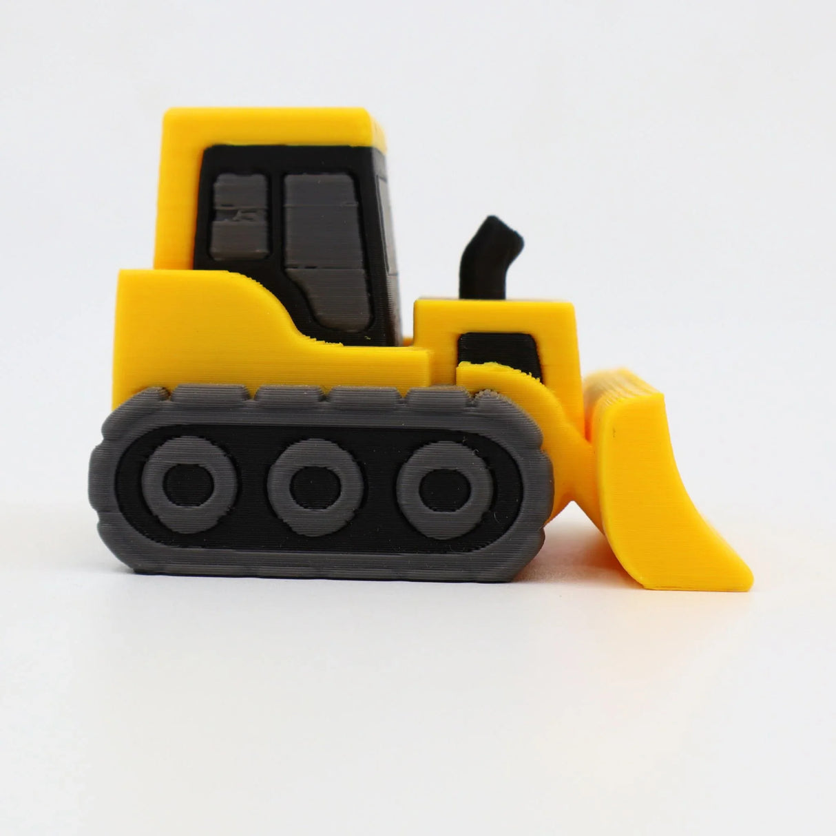 Yellow 3D printed sensory toy bulldozer with black tracks on white background